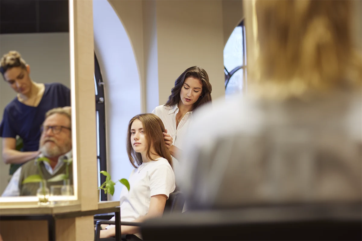 Kvinnliga frisörer med kunder i salong.