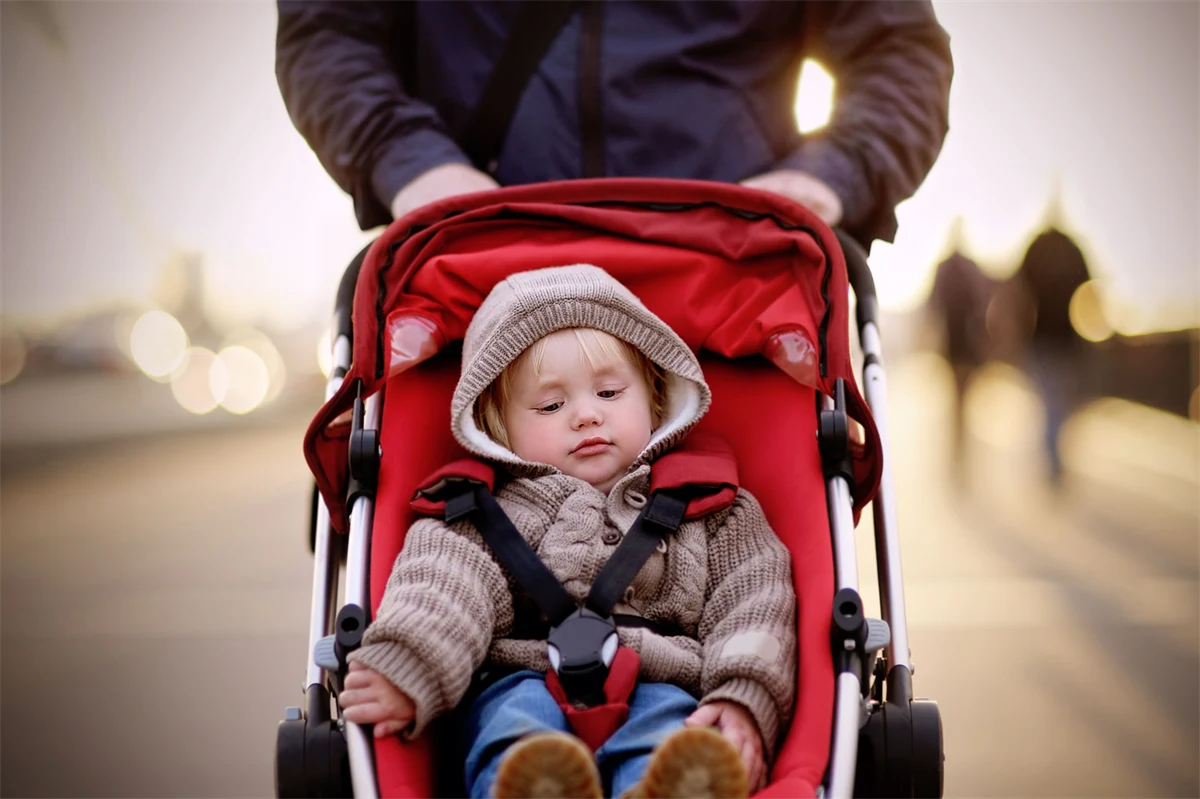 Föräldraledig pappa på promenad med barn i barnvagn